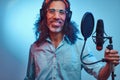 African Rastafarian singer male wearing a blue shirt and beanie emotionally writing song in the recording studio.