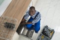 African Repairman Repairing Dishwasher Royalty Free Stock Photo