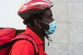 African rider man delivering meal to customers with electric bicycle while wearing face mask during corona virus outbreak