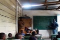 In an African school, a teacher of African ethnicity stands near the blackboard and tells the students a lesson