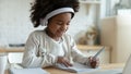 African schoolgirl sit at table writing in workbook studying distantly Royalty Free Stock Photo