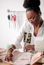African seamstress working with fabric takes measures