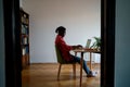 African self-employed guy freelance sits at desk using laptop working remotely in cozy home office Royalty Free Stock Photo