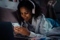 African smiling teen girl liying on bed with phone texting Royalty Free Stock Photo