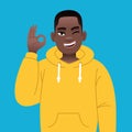 African successful confident boy in yellow hoodie shows ok sign gesture. Happy black young guy with glasses