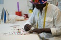 An african tailor drawing outline on a fabric in his sewing shop. Royalty Free Stock Photo