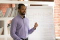 African teacher standing near flipchart with tenses, explaining English grammar