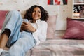 African teen girl liying on bed with phone using apps Royalty Free Stock Photo