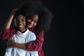 African teen siblings boy and girl hugging with smiley face on black background Royalty Free Stock Photo