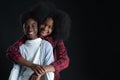 African teen siblings boy and girl hugging with smiley face on black background