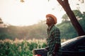 African traveler man hanging film camera with hat stand in the corn plantation field