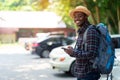 African traveler man using smartphone at car park with holding backpack