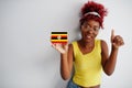 African woman with afro hair, wear yellow singlet and eyeglasses, hold Uganda flag isolated on white background, show thumb up