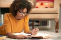 African woman, books and reading on floor in library for learning, relax and study for education. Female student, novel