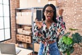 African woman with braids working at small business ecommerce showing smartphone screen annoyed and frustrated shouting with Royalty Free Stock Photo