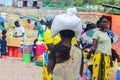 African woman carrying a bag with groceries on her head and a child wrapped in a scarf on her back