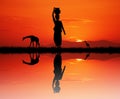 African woman carrying water at sunset