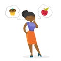 African woman choosing between apple and cupcake. Royalty Free Stock Photo