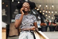 African woman, with colorful shopping bags, talking on mobile phone during christmas shopping at mall Royalty Free Stock Photo