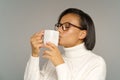 African woman in cozy sweater drinking hot coffee or tea with closed eyes. Winter drinks concept Royalty Free Stock Photo