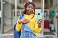 African woman doing video call with smartphone scared and amazed with open mouth for surprise, disbelief face