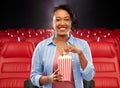 African woman eating popcorn at movie theater Royalty Free Stock Photo