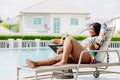 African woman enjoy relax sunbathing on pool bed at village sport club swimming pool sunny day summer season Royalty Free Stock Photo