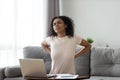 African woman feeling backpain tired of computer sit on sofa