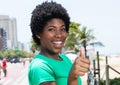 African woman in a green shirt in the city showing thumb Royalty Free Stock Photo