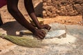 An african woman grinding cereals millet