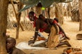 An African woman grinds wheat by rubbing one stone over another while carrying a baby on her back. Royalty Free Stock Photo