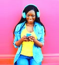 African woman with headphones listens to music over pink Royalty Free Stock Photo