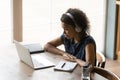 African woman in headset ponder on information at pc screen