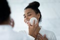 African woman holding facial sponge cleansing face