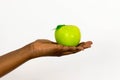 African woman holding out delicious green apple in open palm isolated on a white background Royalty Free Stock Photo
