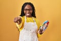 African woman holding painter palette pointing to you and the camera with fingers, smiling positive and cheerful Royalty Free Stock Photo