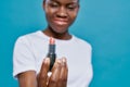 African woman holding and showing pink lipstik close up.