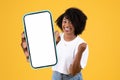 African woman holding smartphone blank touchscreen making yes gesture, studio