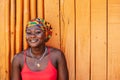 African woman with a hopeful happy smile standing against a painted wooden wall in the tropical village