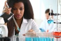 An African woman in laboratory with microscope and liquids in flasks working with them