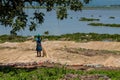 African woman on the lake shore near boat preparing the net for fishing