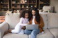 African woman and little daughter using laptop seated on couch
