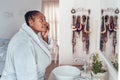 African woman looking at her face in a bathroom mirror