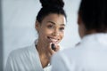 African woman looking in mirror applying lipstick on lips Royalty Free Stock Photo