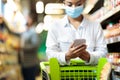 African Woman In Mask Doing Grocery Shopping Using Smartphone Indoors