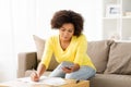 African woman with papers and calculator at home Royalty Free Stock Photo