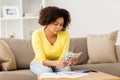 African woman with papers and calculator at home Royalty Free Stock Photo