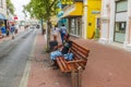 An African woman peacefully napping on a bench surrounded by people and tourists strolling through Willemstad\'s