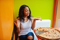 African woman with pizza sitting at bright colored restaurant Royalty Free Stock Photo