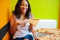 African woman with pizza sitting at bright colored restaurant Royalty Free Stock Photo